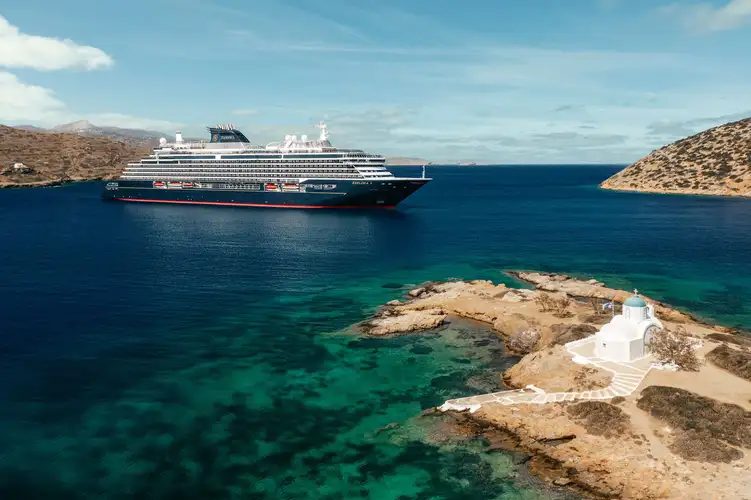 Explora I anchored in a turquoise Mediterranean bay beside a small white chapel